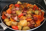 A medley of potato, sausage and veg in a frying pan