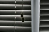 Close up of window blinds, focused on toggle to open and close them