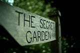 A wooden signpost, carved with the words “the secret garden”