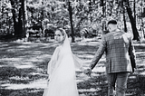 A photograph of a newlywed couple holding hands while the bride looks back and embraces the realization that the perfect marriage is only an idealistic thing.