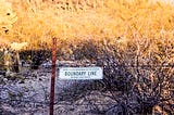 barbed wire fence with sign “Boundary Line”