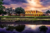 A striped circus tent by a river