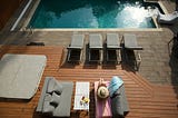A lady reading a book by the pool.