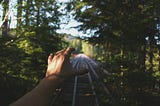 A hand stretched towards a rail track.