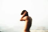 A person holding their head against noise. The picture is blurred and has a pale background.