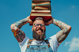 photo of a man with glasses, tattoo and beard, holding many many books, in victory posture, bright and sunny day, AI image created on MidJourney by Henrique Centieiro and Bee Lee