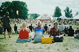 Three women sitting slightly apart from a larger group, symbolizing isolation within a shared space.