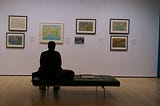 Dr. Marx sitting on a bench looking at paintings at The MOMA.