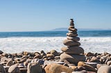 A picture of rocks on a beach with a rock monument in the middle