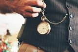 A man wearing a waistcoat and holding a pocket watch.