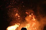 silhouette of a person looking at a large fire