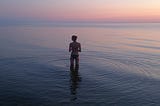 Woman paddling in water at sunset