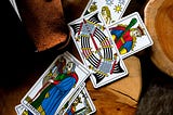 A stack of scattered tarot cards: The Hermit, The Eight of Swords and the Queen of Wands, from the Tarot de Marseilles.