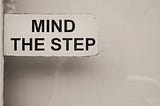 A sign warning to ‘Mind the Step’ indicating a potential tripping hazard or change in floor level ahead.
