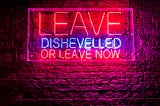 A neon sign that states — Leave Dishevelled Or Leave Now