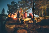 A group of people gathered around a campfire at night, telling stories and connecting face-to-face.