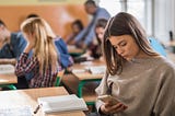 teenager looking at their phone in class