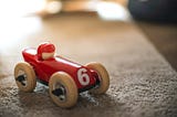 A wooden toy race car and driver.