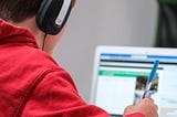 Photo from Unsplash. Home schooling during lockdown, boy working on school work with laptop and headphones.