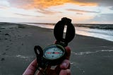 holding a compass on the beach