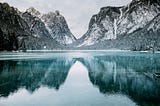 A still lake reflecting snowy mountains around it