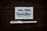 Card with “New Year Resolutions” written on it. A white pen in below the card.