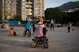 Man in a wheelchair, watching children play