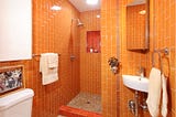 A bathroom tiled with bright orange tiles