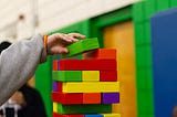 Brightly coloured, wooden building blocks being made into a tower