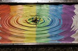 Image of ripples on water that is reflecting the color spectrum.