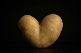 A potato shaped like a heart on a black background