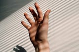 A hand reaching up for help in an office.