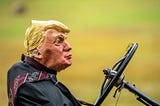 A melting wax figure of Donald Trump sits behind a steering wheel, his tie blowing in the wind.