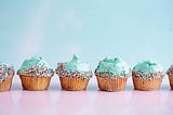 A row of cupcakes with blue icing.