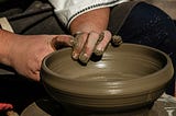 Male hands molding a pot on a potter’s wheel.