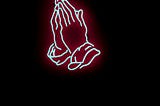 A neon sign in the shape of praying hands