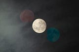 cloudy sky with a lit full moon and muted blue and red planets