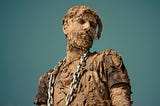A man covered in clay and wearing a chain.