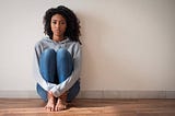 Woman sitting on the floor looking into space.