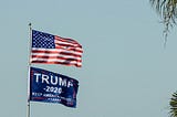 Flagpole with American flag above a Trump 2020 flag