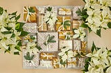 Gold-and-white-wrapped Christmas gifts with white pointsettas