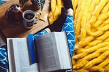 feet with black socks on thick yellow rug with big book on lap