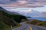 Description from Klanarong Chitmung Peter’s Lookout, Ben Ohau, New Zealand photo is of a road with a mountain in the background, clear sky, and snow.