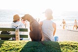 A woman sitting with her dog on the beach