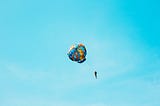 Photo of a person in the air with a colourful parachute