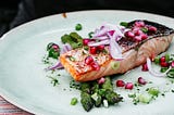 Fish sits on a white plate. The dinner is consistent with a Mediterranean diet.