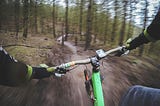 a mountain biker’s perspective from the handlebars rushing down a singletrack in the forest