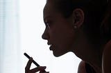 A silhouette of a woman’s face and hand speaking into her phone’s microphone
