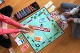 2 people playing Monopoly on the floor