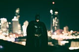 Photo of Batman with night skyline in background.